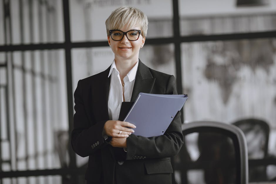Professional woman in a suit holding a folder in a modern office setting.